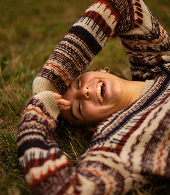 Frau liegt im Gras und lacht